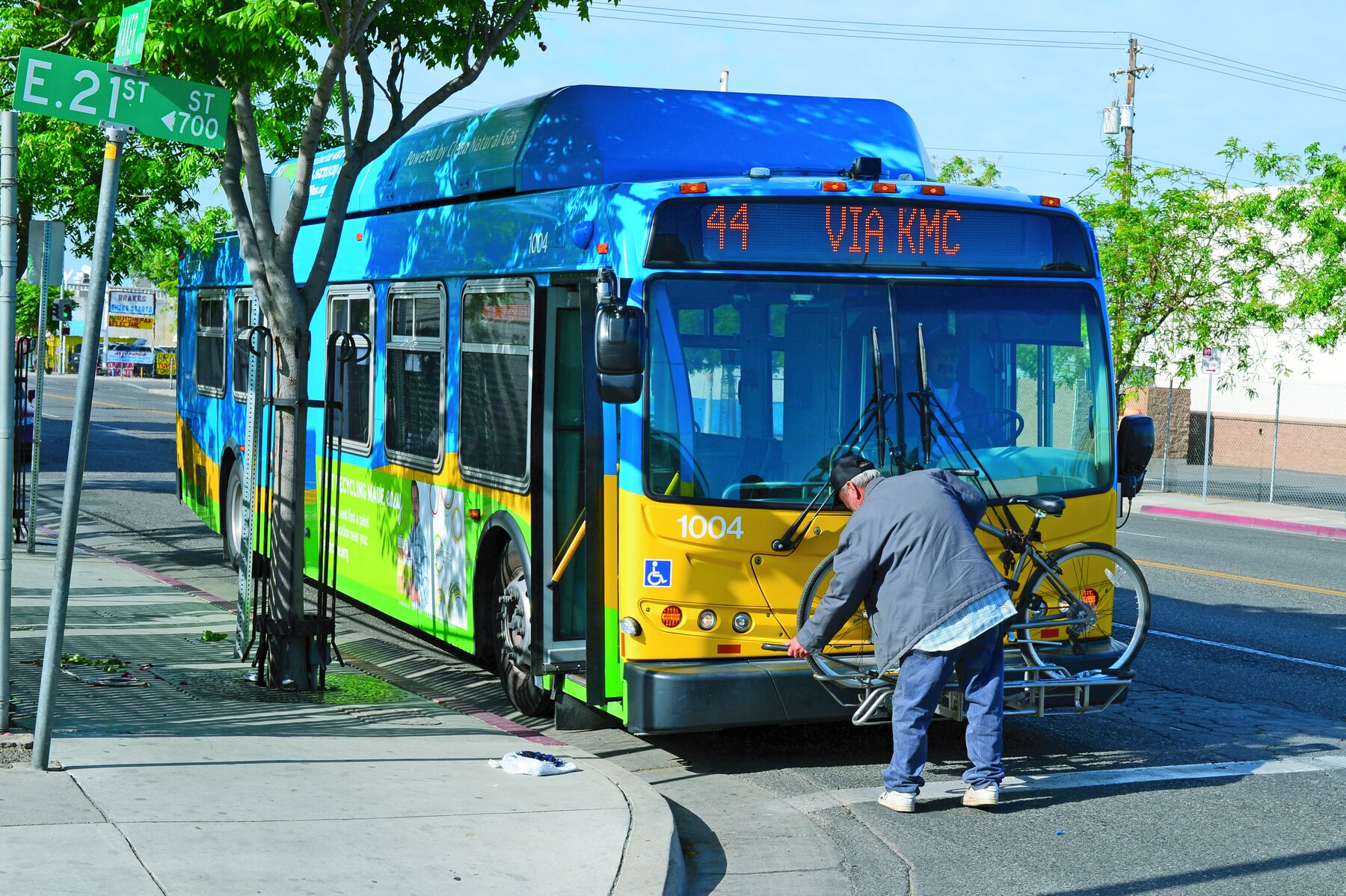 A rider loading a bicycle onto the front rack of a transit bus
