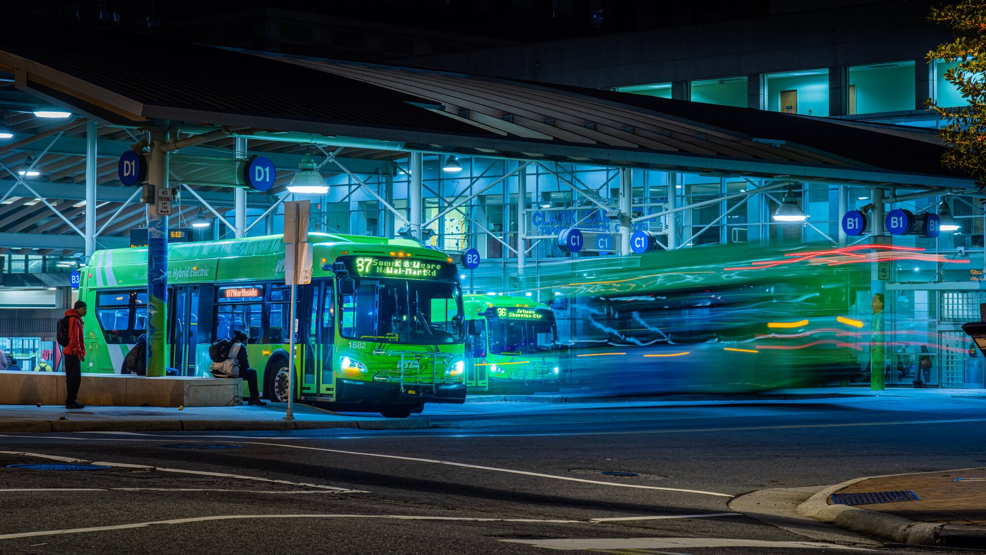 Transit buses at a lit bus terminal at night