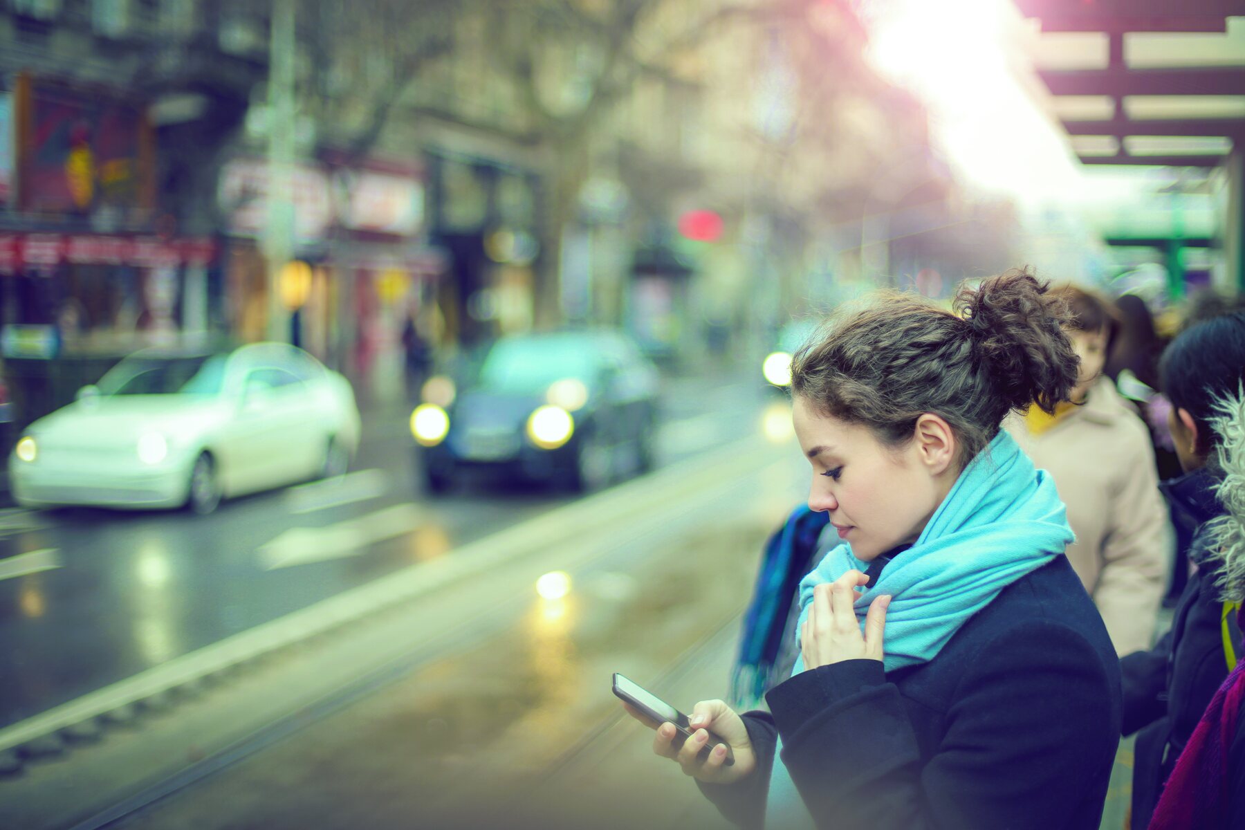 A rider at a transit stop checking her phone
